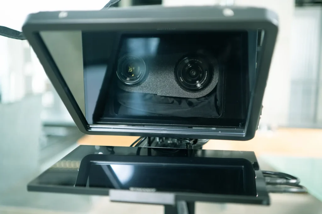 Blick durch den Teleprompter auf die beiden Kameraobjektive